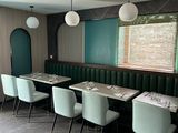 tables and chairs in a restaurant with a green wall and a window