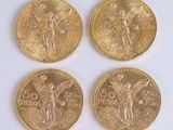 four gold coins sitting on top of each other on a white surface