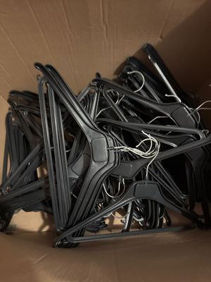 une boîte en carton remplie d'une multitude de cintres noirs