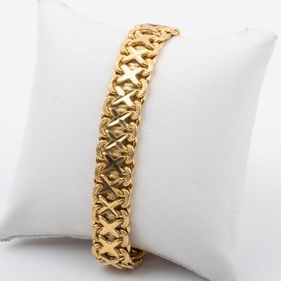a close up of a gold bracelet on a white pillow