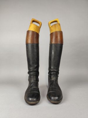 une paire de bottes noires et marron rehaussées de touches jaunes sur fond gris