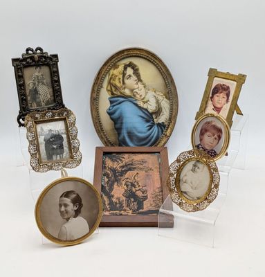 Plusieurs photos encadrées représentant des femmes et des enfants sont exposées dans une vitrine.