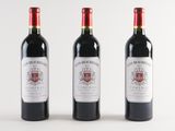 three bottles of red wine are lined up on a white surface