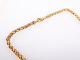 a close up of a gold necklace on a white surface