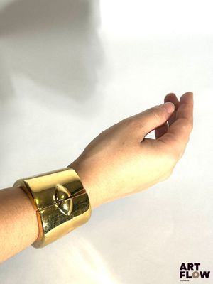 la main d'une femme tenant un bracelet en or orné d'un crâne