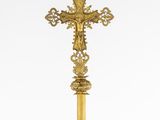 a gold cross on a black stand with a white background