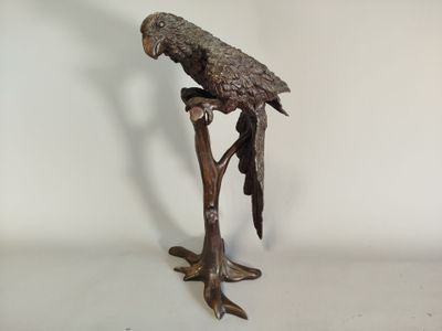 statue représentant un perroquet perché sur une branche d'arbre, sur fond blanc