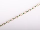 a close up of a green and white bracelet on a white surface