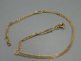 un collier en or avec une chaîne posée sur une surface grise