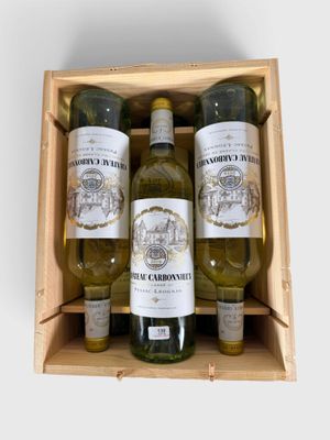 des bouteilles de vin sont disposées dans une caisse en bois posée sur une surface blanche