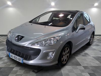 La petite voiture argentée est garée dans le garage, sur le sol à damier.