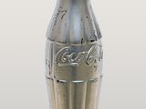a silver coke bottle with a red lid
