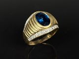 gros plan d'une bague en or avec une pierre bleue
