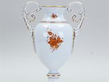 a white vase with orange flowers on it on a table