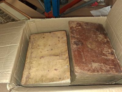 two old books in a cardboard box on the floor