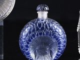 a blue glass bottle sitting on a table next to a mirror