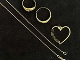 two gold rings and a necklace on a black surface