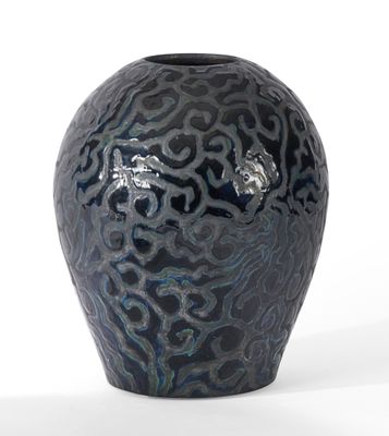 a black vase with a pattern on it on a white surface