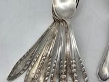 silver spoons and spoon rest on a white surface with a pair of scissors