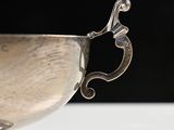 an antique silver cup on a white table with a black background