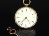 a gold pocket watch and a key on a black surface