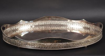 une assiette ancienne en argent aux bords incurvés, sur fond noir