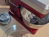 a red mixer on the counter with a plastic bowl on it