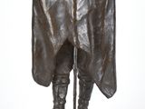 statue en bronze représentant un homme vêtu d'une cape et coiffé d'un chapeau, assis sur un rocher
