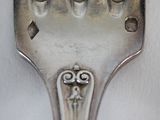 a silver fork with a design on it on a white surface