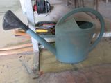a blue watering can sitting on the floor next to a hose
