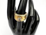 a black hand with a gold ring on it and a diamond ring on the middle finger