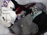 a pile of clothes in a basket on a bed