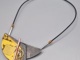 a close up of a necklace with a piece of metal on it