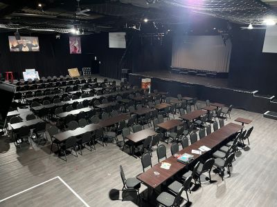 a large room with tables and chairs and a projector screen on the wall