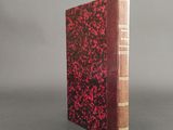 an old book sitting on top of a table with a red cover