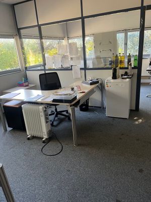 une pièce équipée d'un bureau, de chaises et d'un réfrigérateur