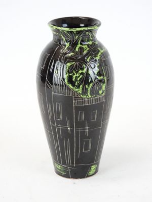 un vase noir orné de motifs verts sur fond blanc