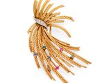 a gold and diamond broochle with multi colored stones