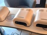 three air purifiers sitting on a desk next to a chair