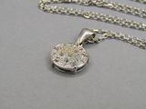 un gros plan d'un collier en argent orné d'un disque en diamant suspendu à une chaîne