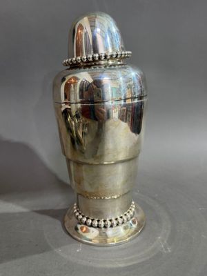 a silver vase sitting on a table with a silver lid