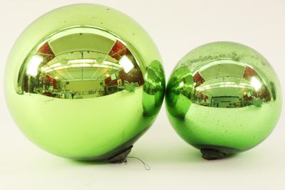 two shiny green christmas balls sitting next to each other