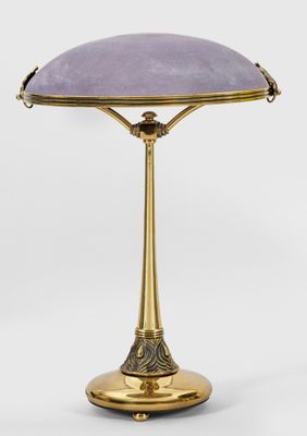 une lampe de table en laiton surmontée d'un abat-jour violet
