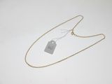 a gold necklace with a tag on it sitting on a white surface