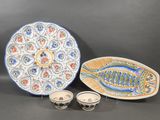two plates and two bowls with fish designs on them