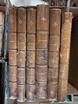 several old books are stacked on top of each other in a box
