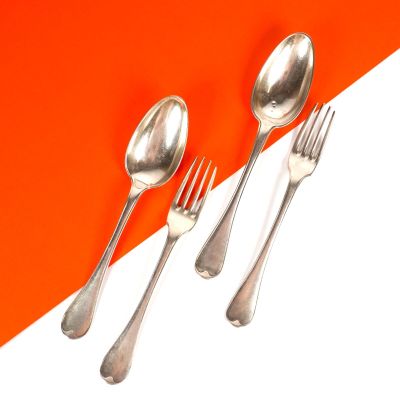 trois cuillères en argent et deux cuillères en argent sur un fond orange et blanc