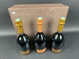 three bottles of wine sit in front of a cardboard box