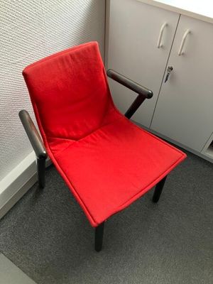 une chaise rouge qui se trouve dans le coin d'une pièce