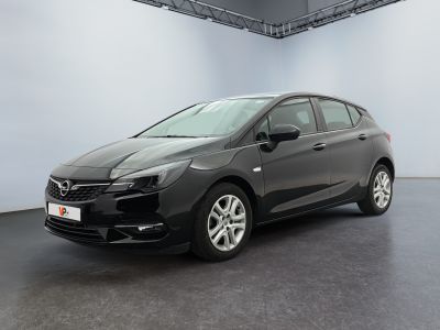 L'Opel noire est garée dans une grande pièce aux murs blancs.